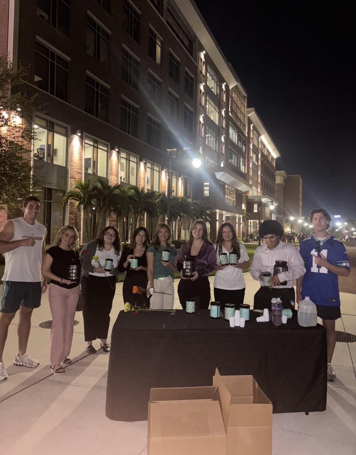 A group gathered behind a table during an outdoor evening event