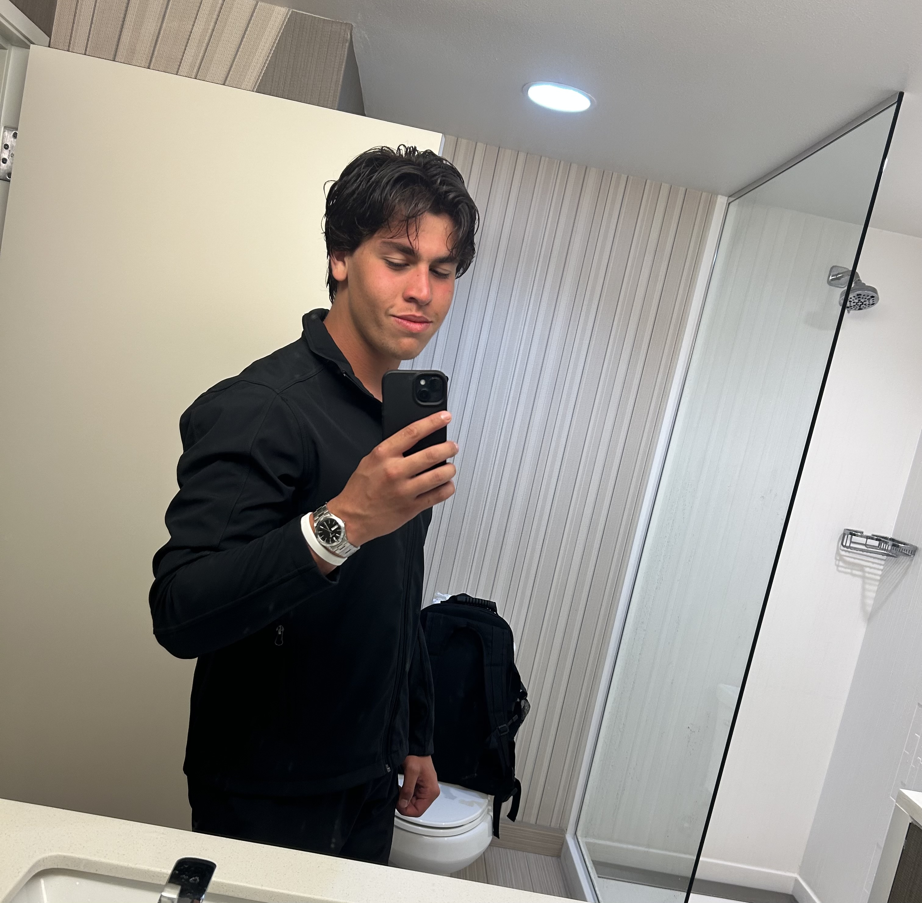 Cristian taking a mirror portrait while wearing a black jacket