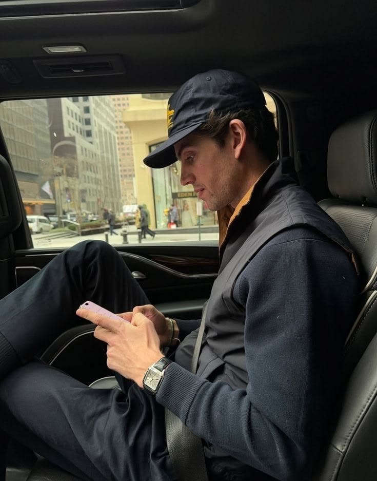 Man seated in a car reading his phone in the city