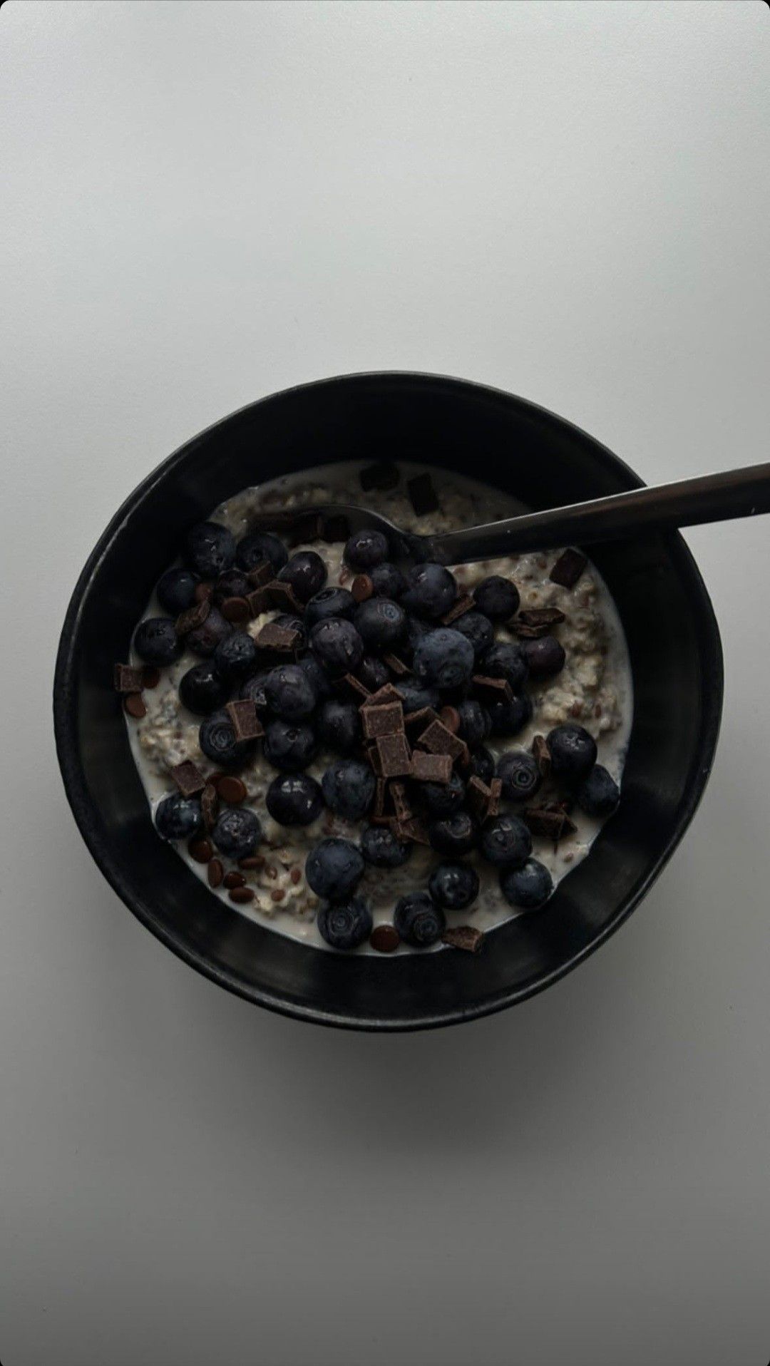 Oats with blueberries and dark chocolate in a black bowl