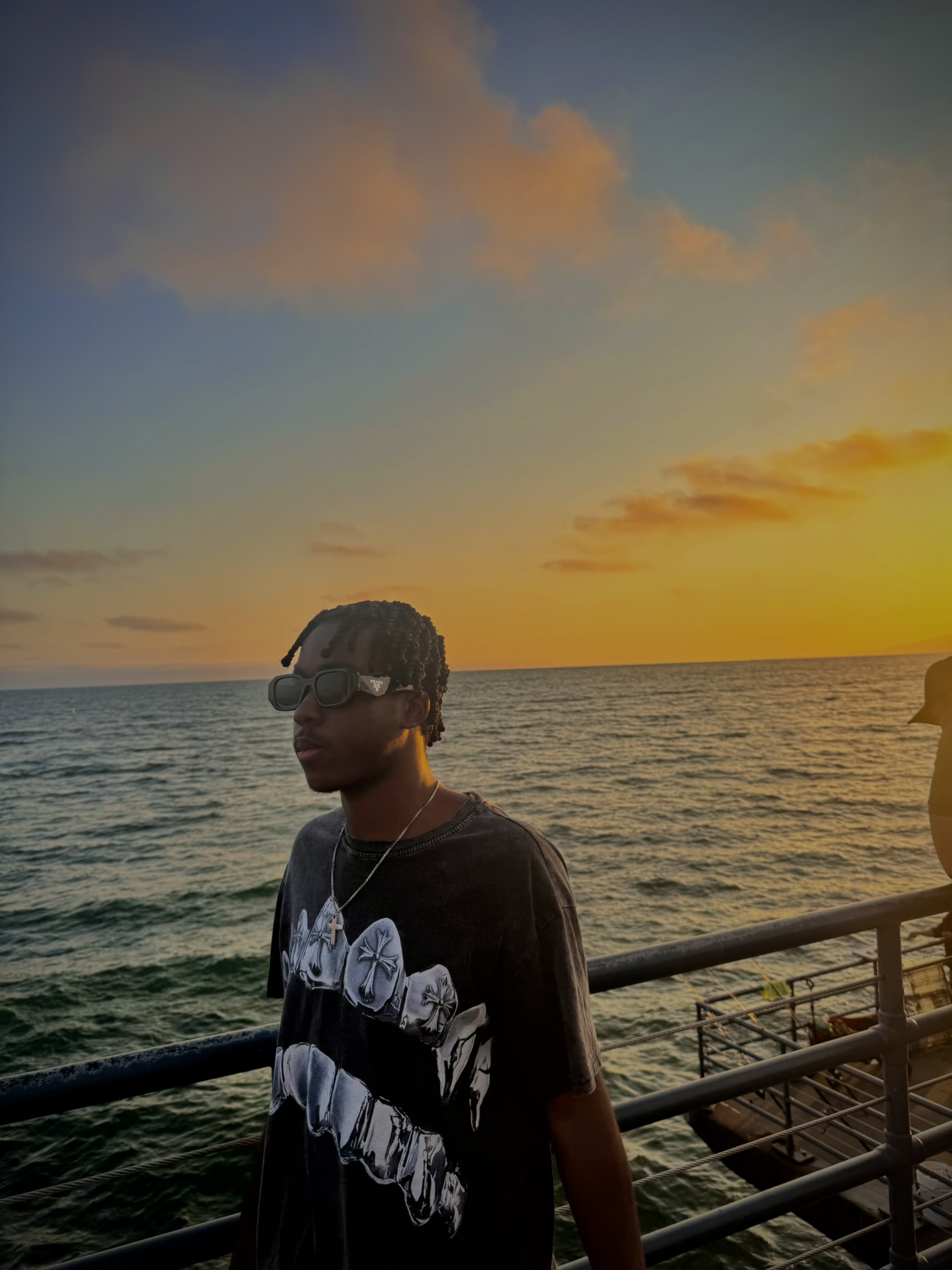 Amir standing beside the ocean at sunset