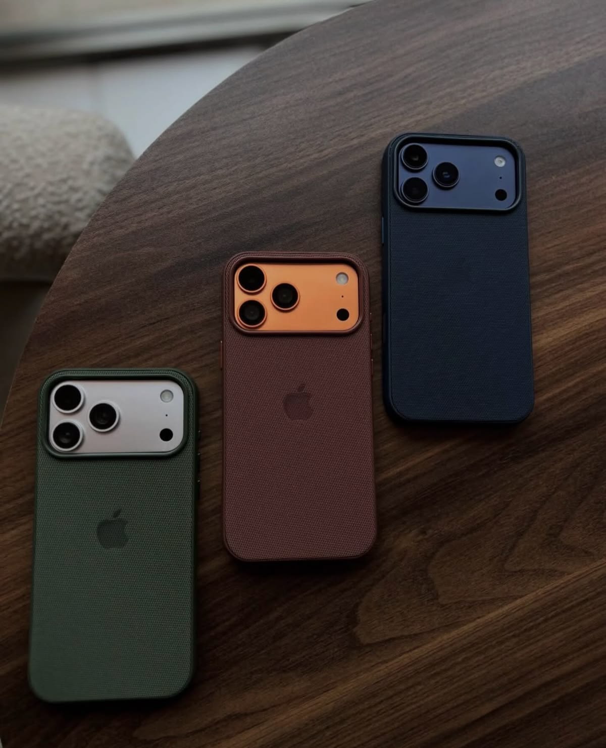 Three textured phone cases on a wood table