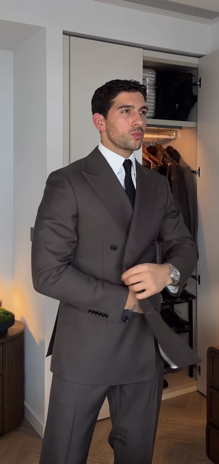 Man wearing a dark brown suit beside an open closet