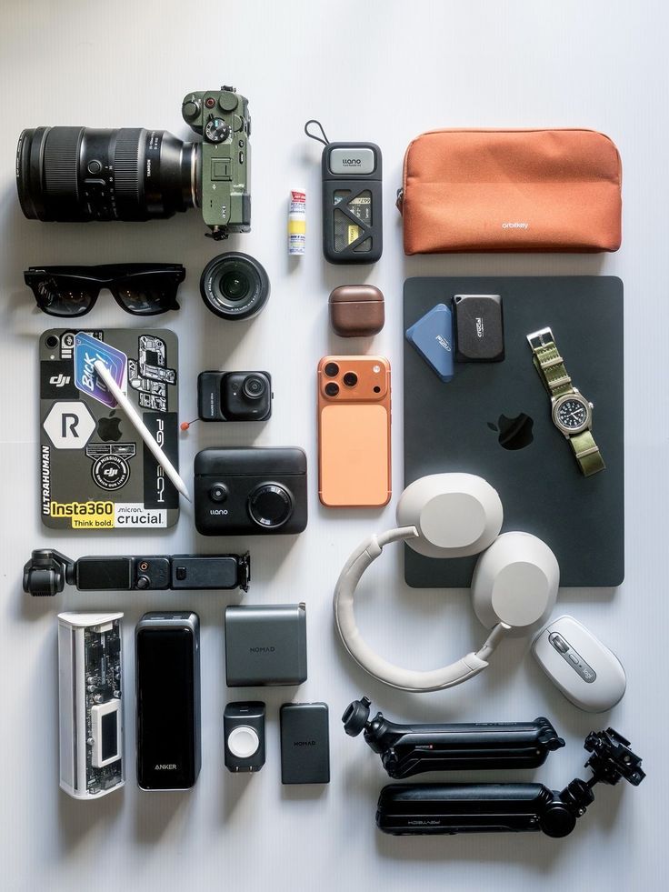 Everyday carry layout with camera, laptop, watch, headphones, phone, and tech accessories