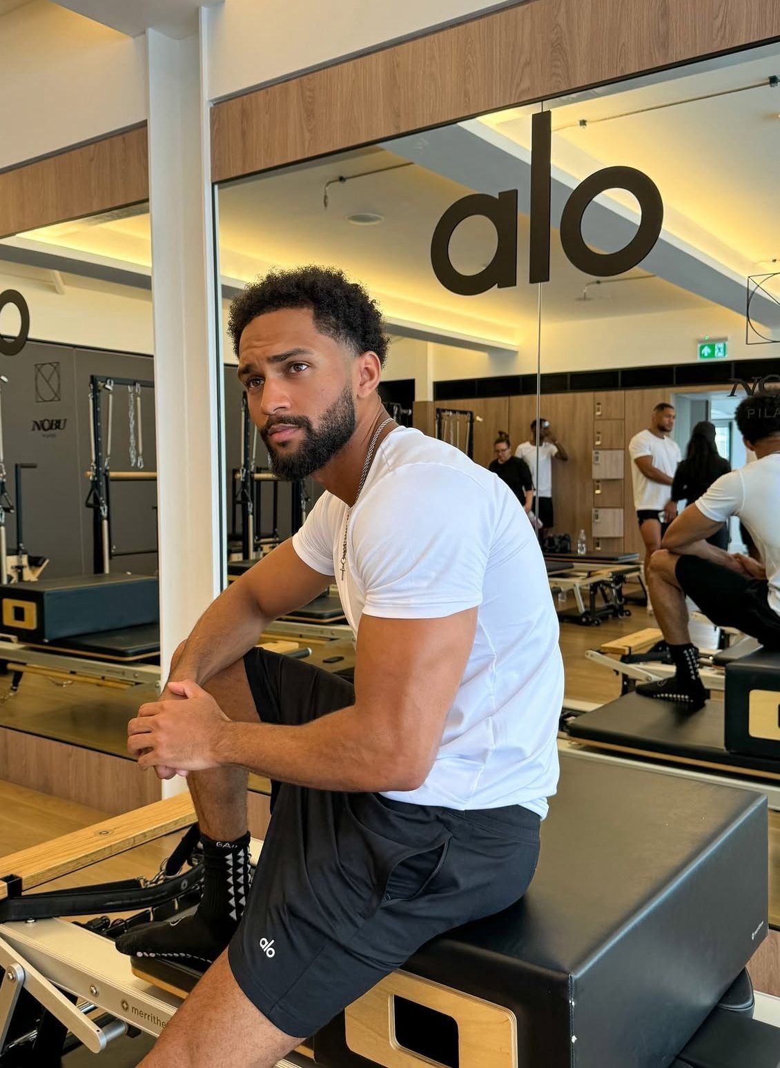 Man in a gym wearing a fitted white shirt and black shorts