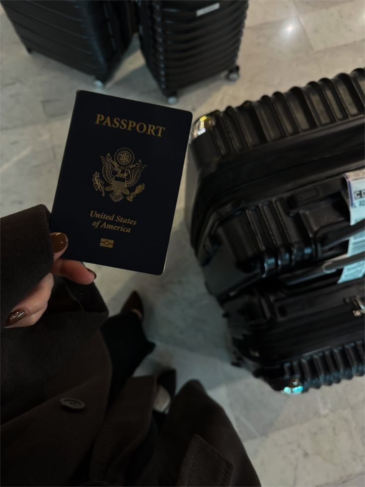Passport held above black luggage at the airport