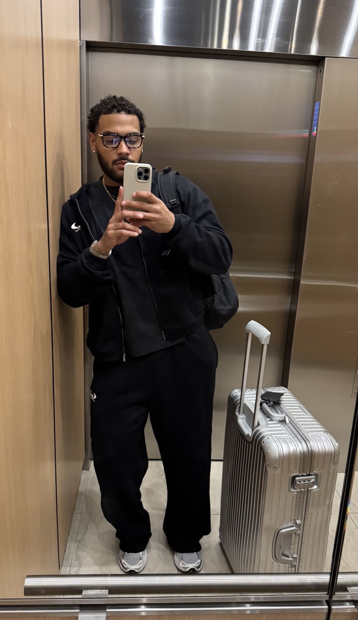 Man in a black travel outfit with suitcase in an elevator